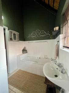 a bathroom with a bath tub and a sink at Tranquil Bush Cottage at Kruger in Marloth Park