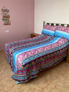 a bed with a colorful blanket on top of it at Cortijo Estrella in Serón