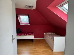 a room with two beds and a red wall at Gasthaus Wicky in Hemdingen