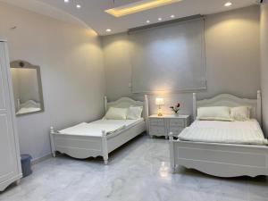 2 weiße Betten in einem Zimmer mit Spiegel in der Unterkunft عين دبي للشقق المفروشة-عائلات in Ta'if