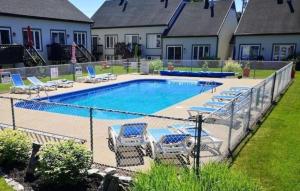a fence with chairs and a swimming pool at Le Repère du Mont-Saint-Anne in Beaupré