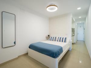 una camera da letto bianca con un letto e uno specchio di Apartamento Primera línea playa a Las Palmas de Gran Canaria