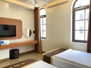 a bedroom with a bed and a tv and windows at Lê Tâm E678 Hotel in Ha Long