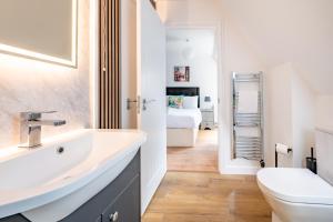 a bathroom with a sink and a toilet and a bedroom at Swift Host - Friars Quay - Riverside - Sleeps up to 8 - Free Parking - City Centre in Norwich +28 photos