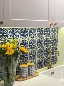 a vase filled with yellow flowers on a kitchen counter at Sea Colours Apartment Budva in Budva +21 photos