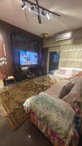 Una sala de estar con dos camas y un televisor de pantalla plana. en Room in shared house, en New cairo