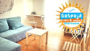 a living room with a blue couch and a sign at Gospoja Park & Beach Apartment Vrbnik in Vrbnik