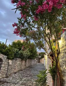 a tree with pink flowers on a stone road at Lithos Areopoli Traditional House in Areopoli