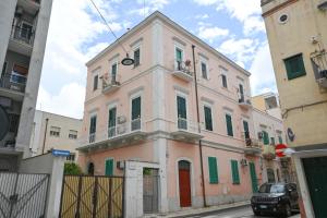 a pink building with green shutters on a street at Cadorna 30 Guest House in Monopoli