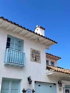 a white house with a clock on the side of it at Encanto Azul in Villa de Leyva