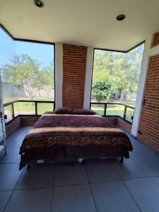 a large bed in a room with large windows at Casa de campo con alberca in Tlayecac