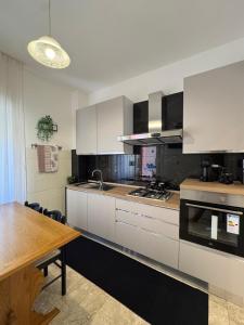 a kitchen with white cabinets and a wooden table at Prestige Rooms in Reggio Calabria