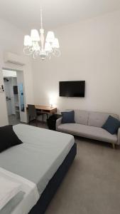 Un dormitorio con una cama, un sofá y un televisor. en Foresteria del Genio - Luxury Suites & Urban Spa, en Palermo