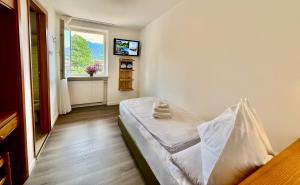 a small bedroom with a bed and a window at Hotel Latemar in Castello di Fiemme