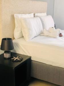 a bed with white pillows and a table with a lamp at Secret-Meadow Accommodation in Maun