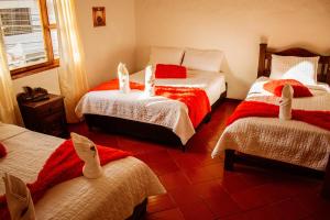 a bedroom with three beds with red and white sheets at Apartahotel Casa de Angel in Villa de Leyva +39 photos