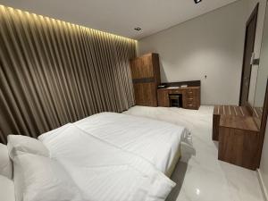 a bedroom with a large white bed and a desk at جوهرة الكروان للشقق المخدومة in Medina