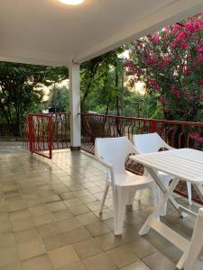 a porch with two white chairs and a table at Utjeha house Ana in Utjeha +8 photos