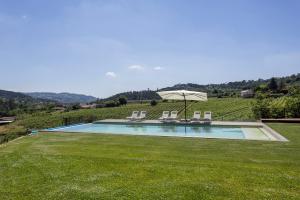 a swimming pool with chairs and an umbrella at Casa do Cipreste em Amarante in Gatão