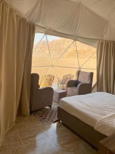 a bedroom with a bed and chairs in a tent at Rum Royal Dunes Camp & tour in Wadi Rum +129 photos