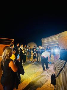 a group of people standing around in the sand at night at Rum Royal Dunes Camp & tour in Wadi Rum