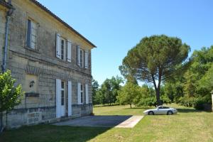 a car parked next to a building with a tree at Maison de maître - proche de Saint Emilion in Gardegan-et-Tourtirac