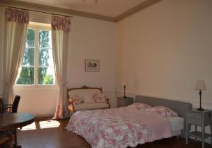 a bedroom with a bed and a table and a window at Maison de maître - proche de Saint Emilion in Gardegan-et-Tourtirac
