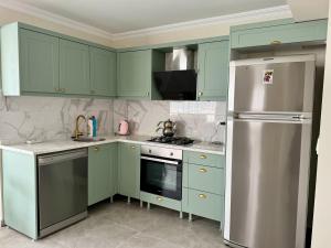 cocina con armarios verdes y nevera de acero inoxidable en Villa Derin, en Okçular