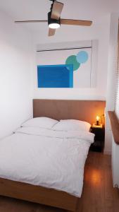 a bedroom with a white bed with a ceiling fan at Rumia Cichy Zaułek 2 in Rumia