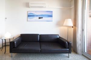 un sofá de cuero negro en una sala de estar con lámpara en Bordeta, en Barcelona