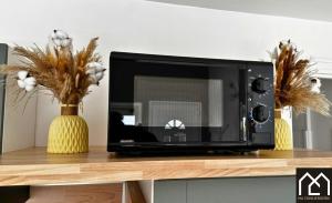a microwave on a counter with two vases with flowers at Maison Cocooning Equihen 5 pers Proche Mer & Terrasse in Équihen-Plage +32 photos