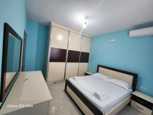 a bedroom with a bed and a blue wall at Villa Arilena in Sarandë