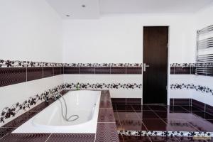a bath tub in a bathroom with black and white tiles at Sweet Home Bucovina- Baza perfecta pentru explorarea Bucovinei in Frasin +59 photos