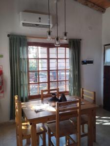 a dining room table and chairs with a large window at Casas HG-Desayuno sencillo entregado al check in-Pileta climatizada en predio a 2 kilómetros-Acepta mascotas bajo petición-Cochera para 1 auto in Huerta Grande