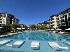 a large swimming pool with lounge chairs and buildings at Oasis Beach Club - "Valencia'' apartment in Lozenets