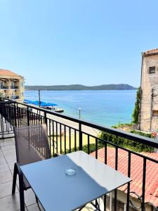 a table and chair on a balcony overlooking the water at Alexis Apartments in Pylos