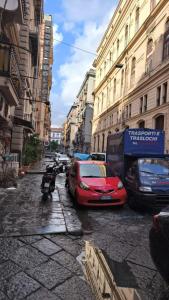 un coche rojo estacionado en una calle de la ciudad con edificios en Caratteristica home, en Nápoles