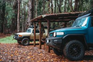 two trucks parked next to each other in the woods at Fully Decked Blue FJ Cruiser! in Kapaa