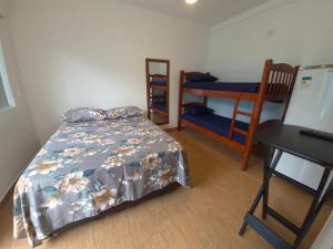 ein Schlafzimmer mit einem Bett, einem Tisch und einem Schreibtisch in der Unterkunft Hospedagem Econômica Flor de Maria 2 in Caraguatatuba + 8 Fotos