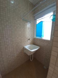 ein weißes Waschbecken im Bad mit Fenster in der Unterkunft Hospedagem Econômica Flor de Maria 2 in Caraguatatuba