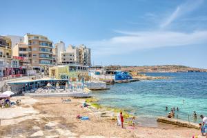 a group of people on a beach near the water at The Apateu in St Paul's Bay