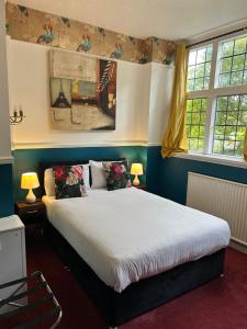 a bedroom with a bed and two windows at Barons Court Hotel in Wolverhampton