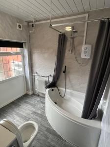 a bathroom with a tub and a toilet and a shower at Barons Court Hotel in Wolverhampton