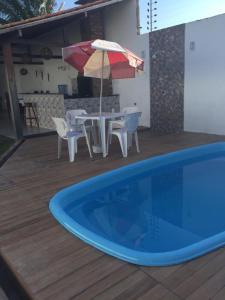 a swimming pool with chairs and a table with an umbrella at Casa em Salinas Pá in Salinópolis +14 photos