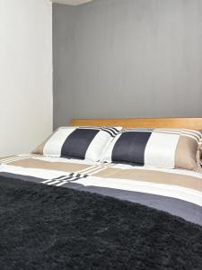 a bed with black and white pillows on it at Room Airport in Bogotá