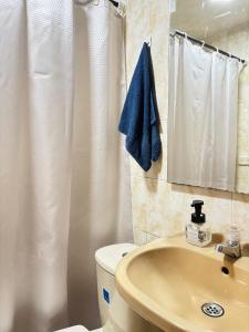 a bathroom with a white shower curtain and a sink at Room Airport in Bogotá