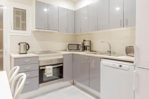 uma cozinha com electrodomésticos brancos e armários brancos em Autèntic Arc de Triomf Apartment em Barcelona