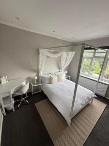 a bedroom with a white bed and a desk at Alross Guest House in London