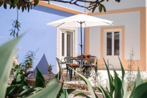 a table and chairs with an umbrella on a patio at Casinhas do Arco da Velha in Palmela