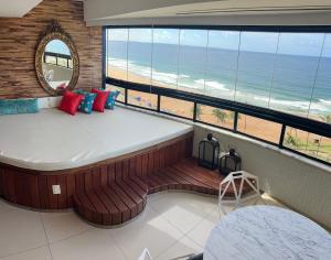 a room with a large bed with a view of the beach at Luxuoso Apart-hotel Beira-mar in Salvador